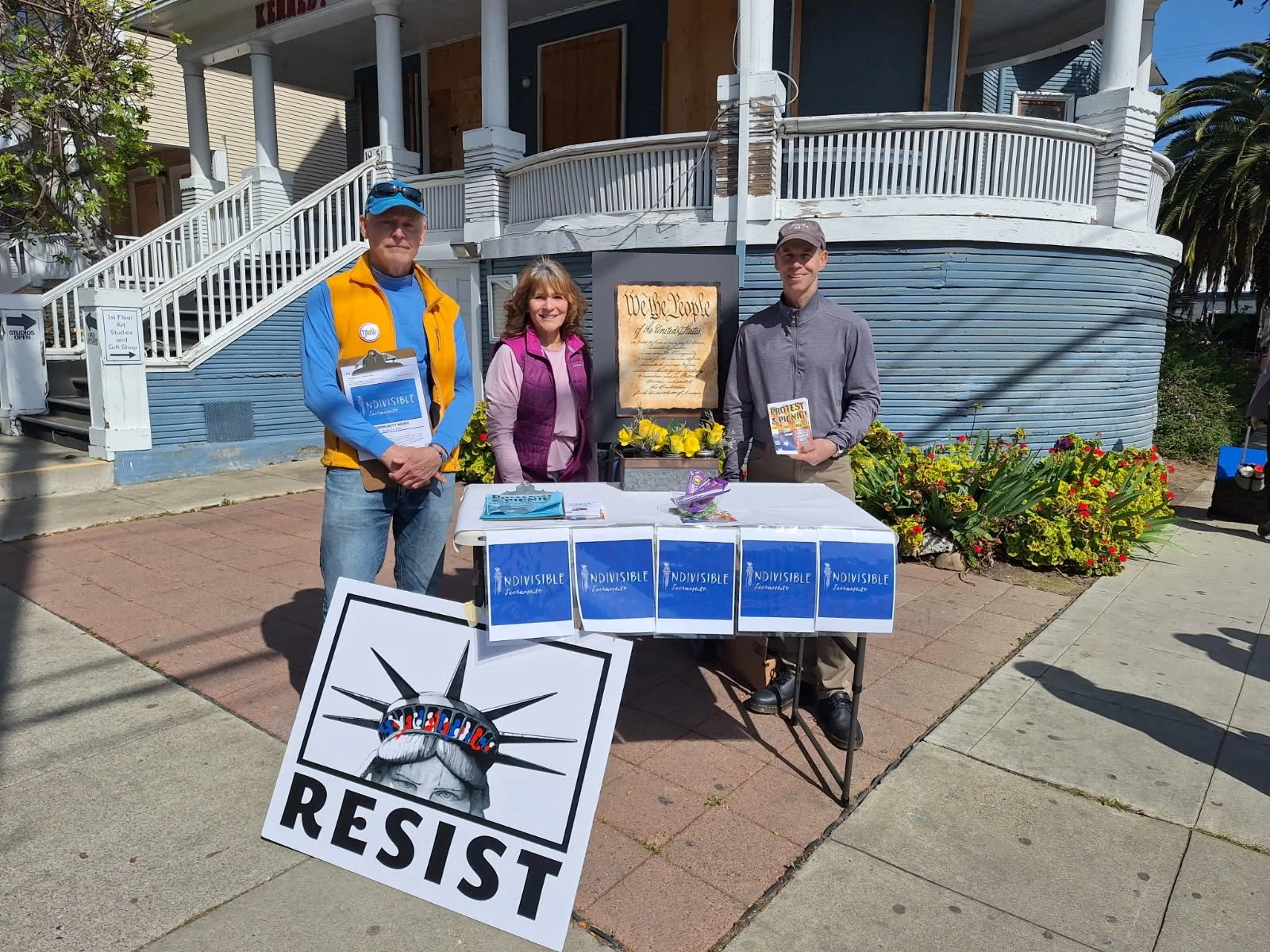 RAEB volunteers tabling with a Resist sign